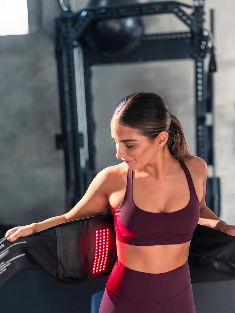 Frau mit 4-in-1 Rückenbandage, in einem Fitnessstudio.