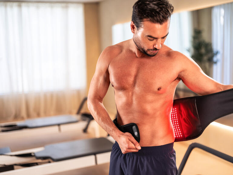 Mann mit 4-in-1 Rückenbandage, die sie anlegt.