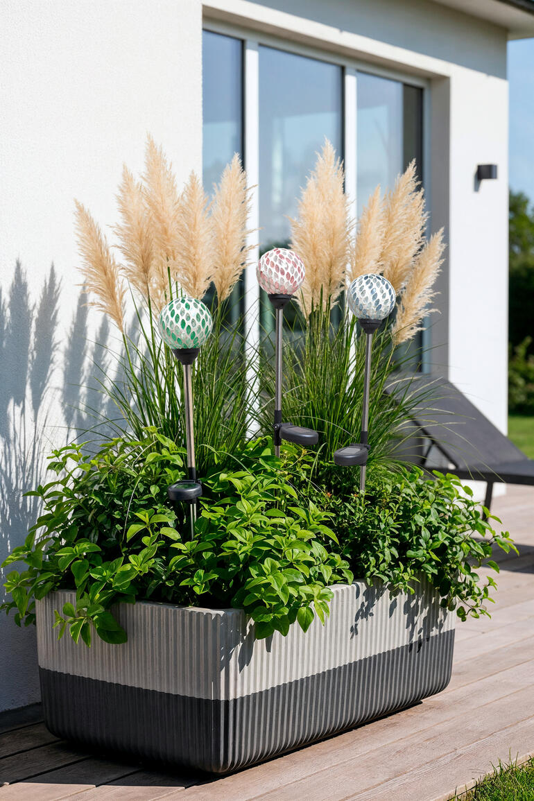 Solargartenstecker in einem Balkonpflanzer mit Ziergräsern.