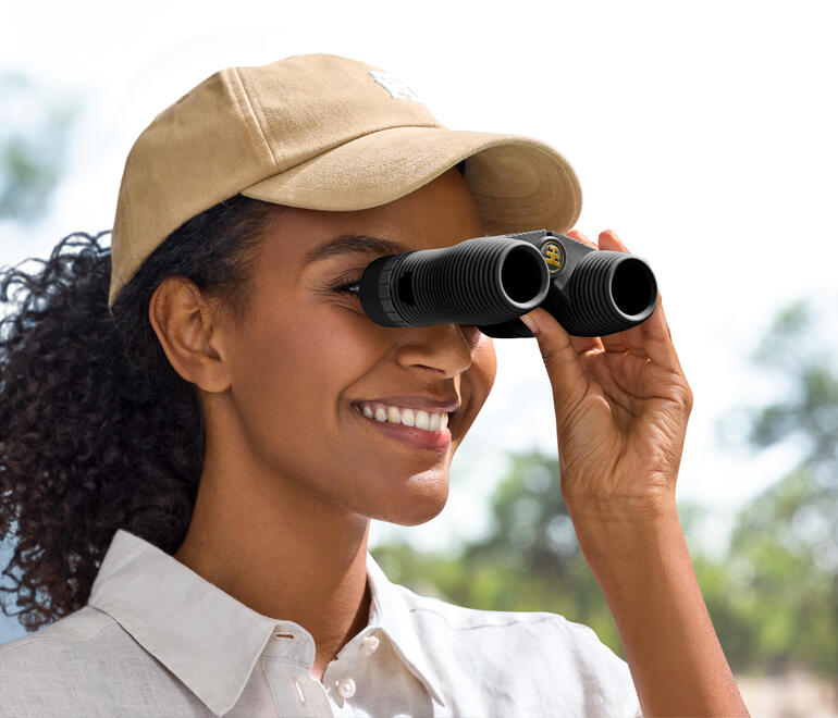 Frau schaut durch ein Kompakt-Fernglas in der Natur.
