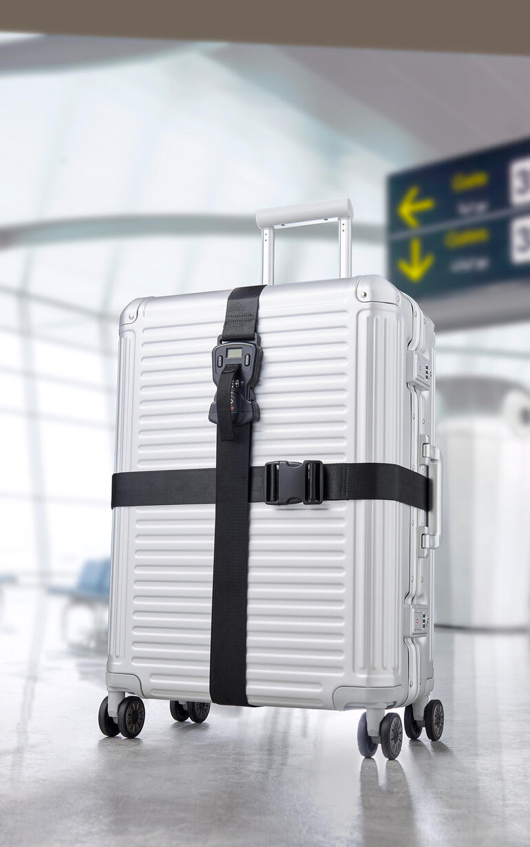 Silberner Koffer mit schwarzem Premium-Koffergurt-Set 3-in-1 auf einem Flughafen.