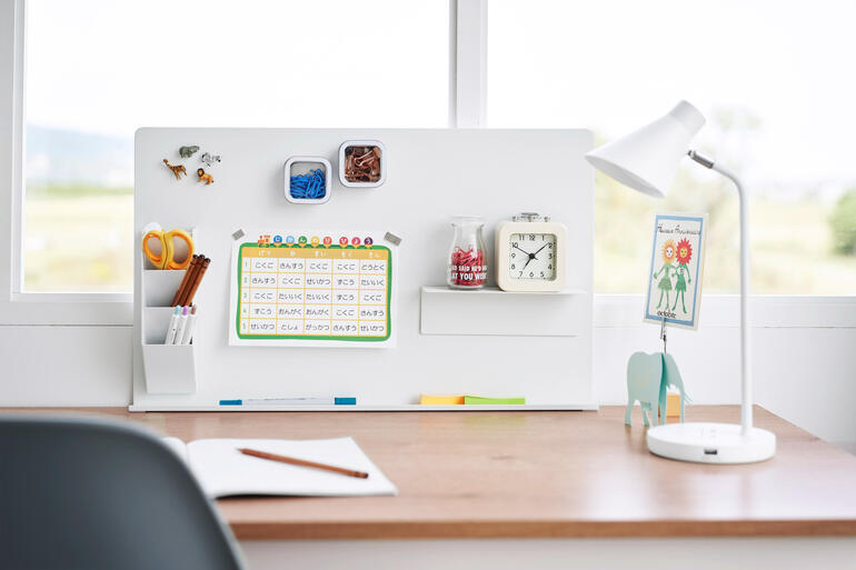 Weißes magnetisches Pinnwand mit Bürobedarf auf einem Schreibtisch.