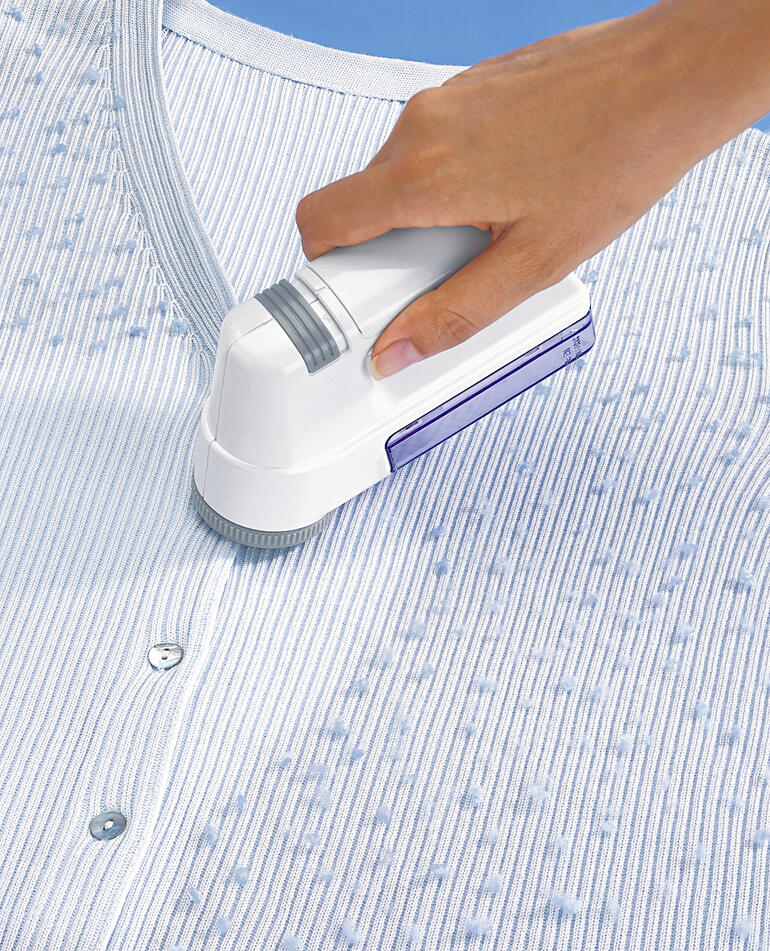 Wollrasierer wird verwendet, um Fusseln von einem gestreiften Pullover zu entfernen.