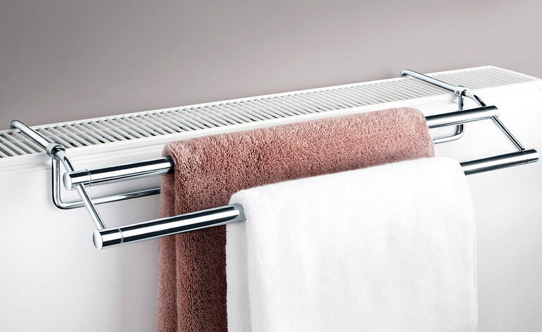 Handtuchtrockner montiert über einem Heizkörper mit Handtüchern.