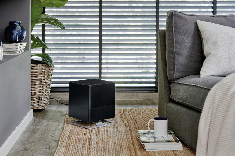 Luftbefeuchter Oskar in Schwarz, in einem Raum mit Sofa und Pflanzen.