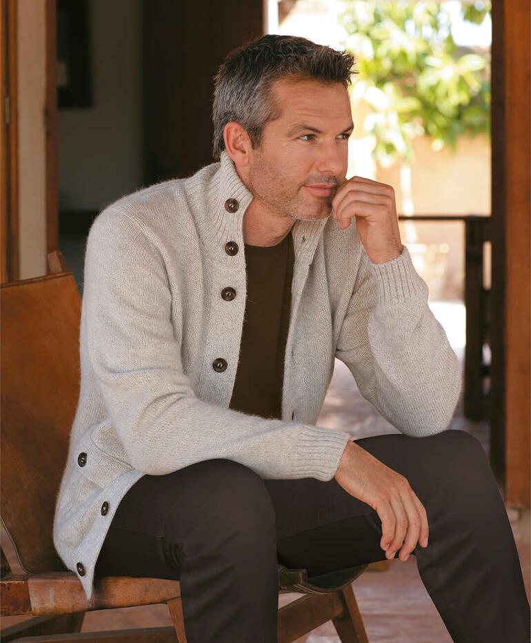 Nahaufnahme eines Mannes in grauer Strickjacke aus Royal-Alpaka, mit nachdenklichem Gesichtsausdruck.