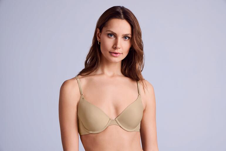 Frau in cappuccinofarbenem Maidenform T-Shirt-BH auf weißem Hintergrund
