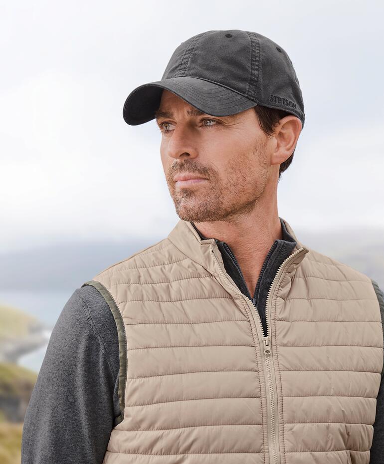 Stetson Baseball-Cap Mann mit Stetson Baseball-Cap und Weste im Freien, mit Blick auf eine Landschaft.