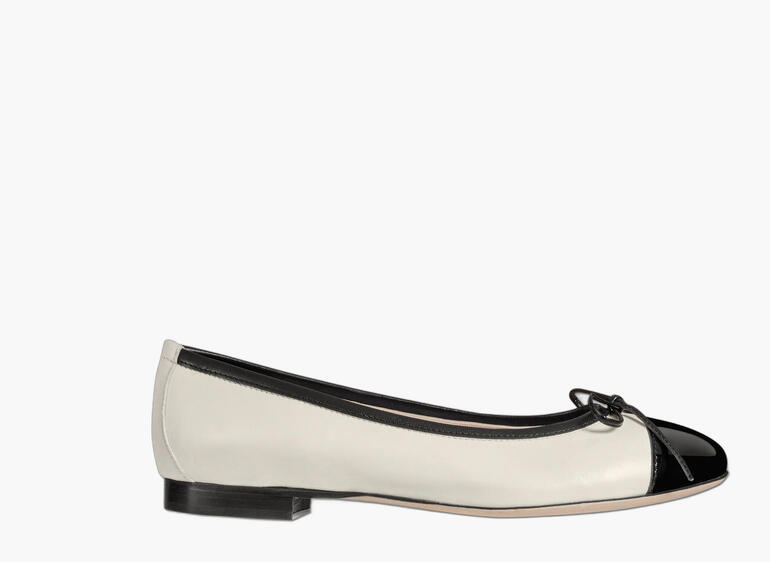Ballerina in Creme und Lack-Schwarz mit Schleife, seitliche Ansicht.