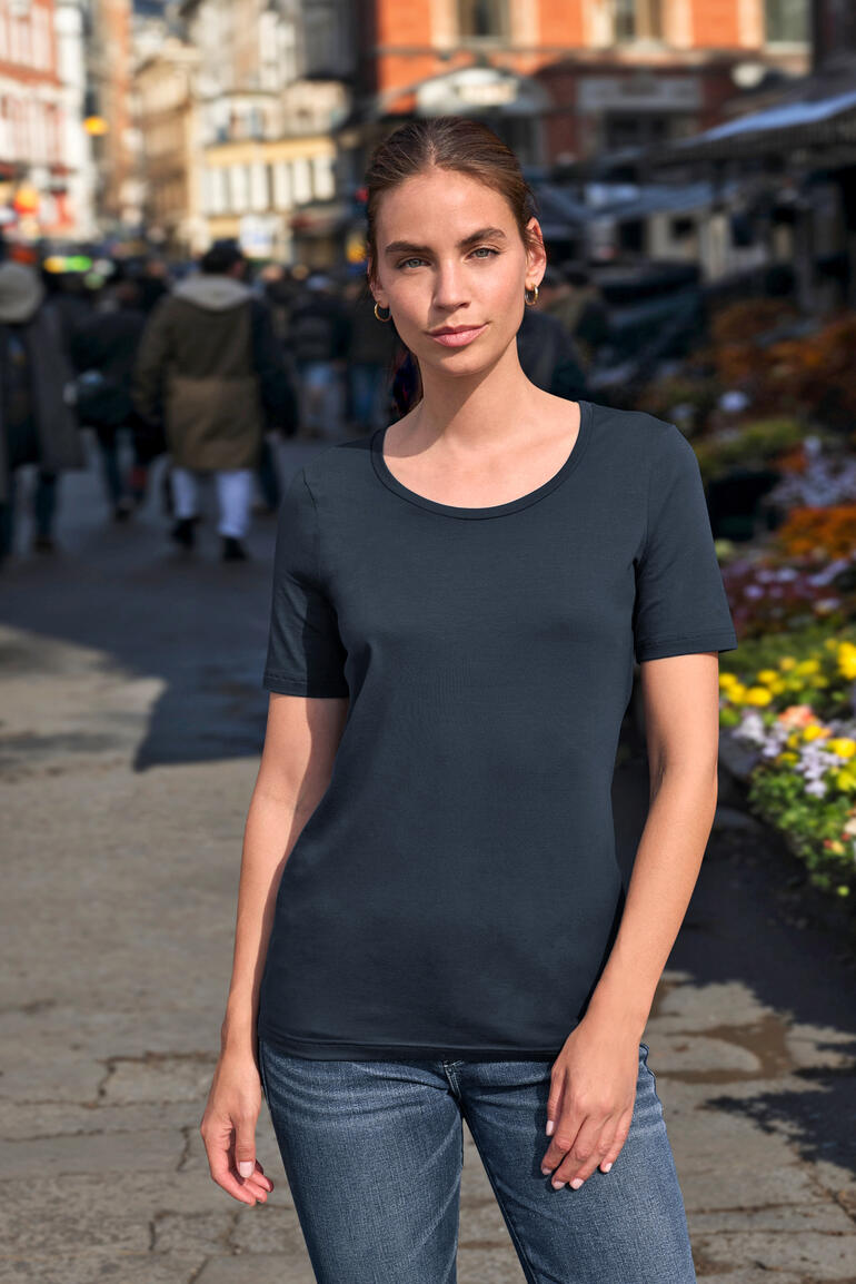 Frau trägt ein marinefarbenes Kurzarm-T-Shirt in einer Stadtstraße.