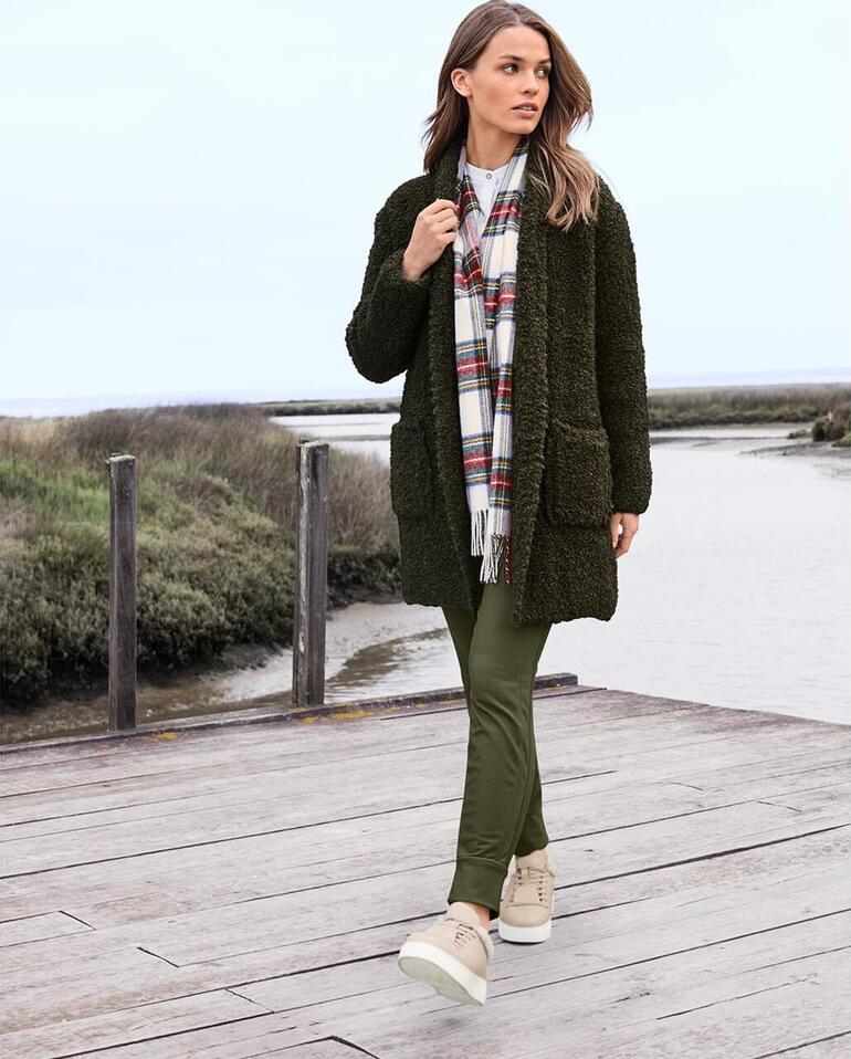 Frau geht am Wasser in Stehmann City-Thermo-Jogger-Pants und Strickjacke.