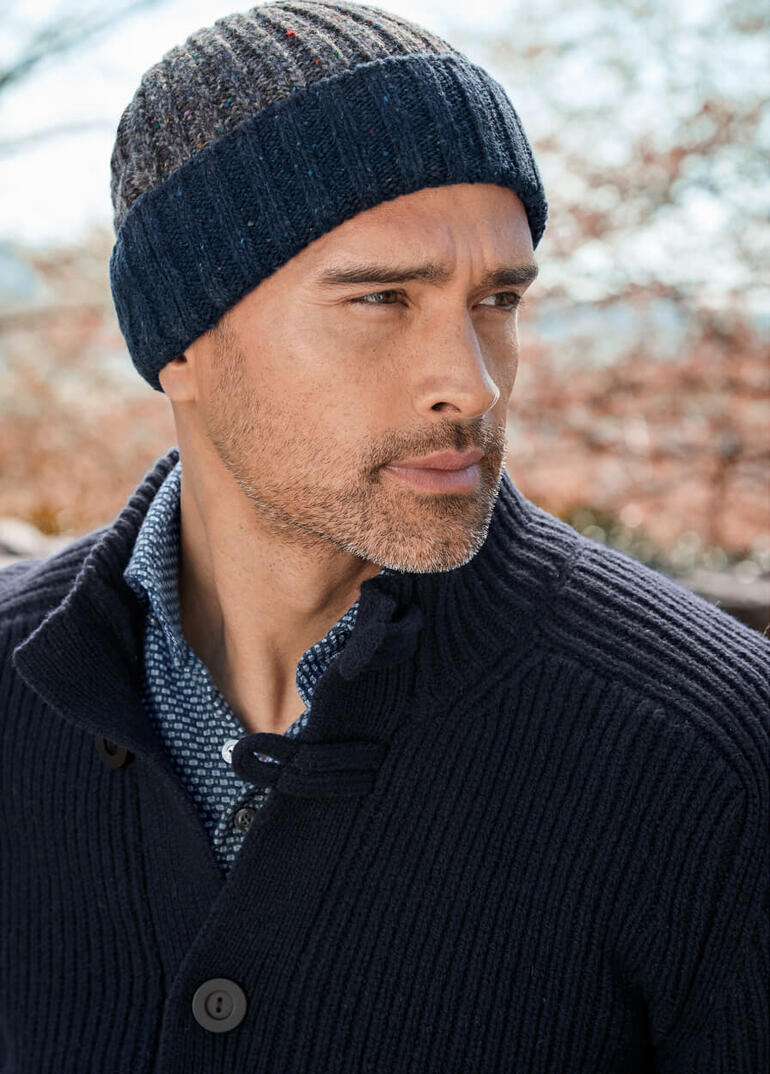 Mann trägt einen gestreiften Bonnet Donegal aus Wolle, mit neutralem Gesichtsausdruck.