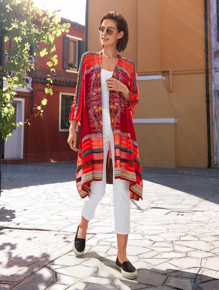 Frau in Rot mit IVKO Kimono-Strickjacke, läuft auf einem gepflasterten Platz