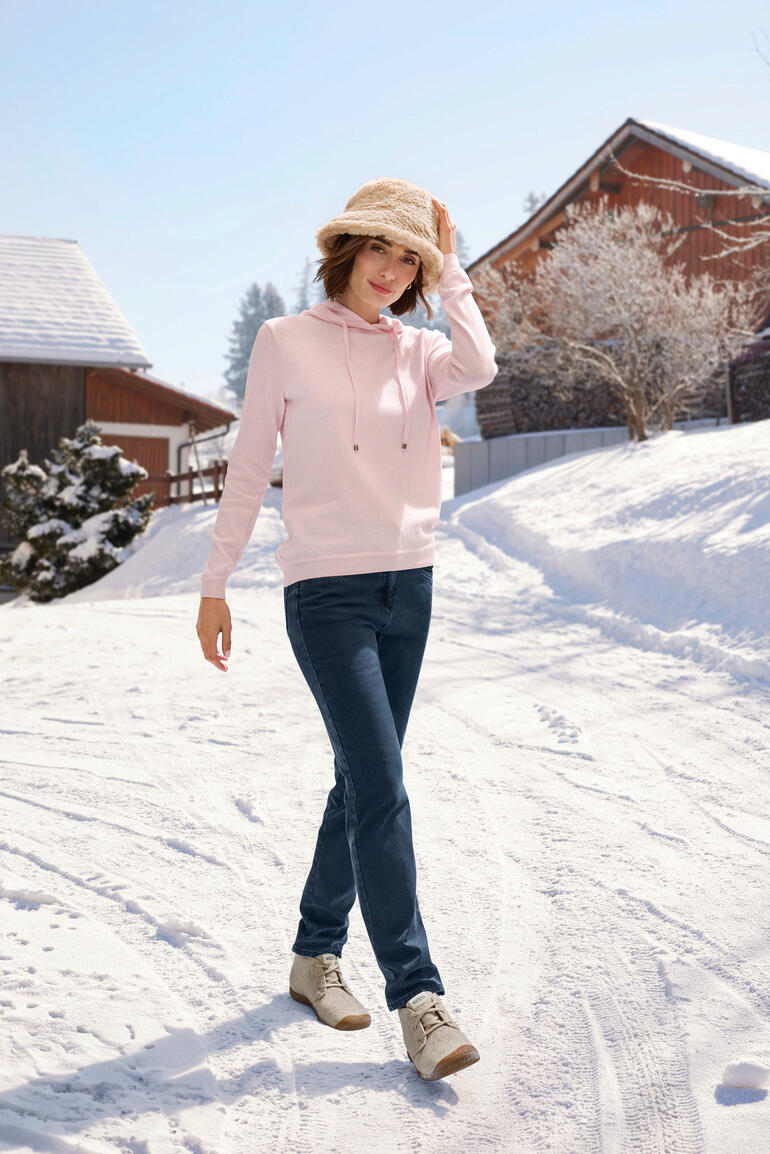 Teddy-Bucket-Hat Frau trägt einen rosa Hoodie aus Baumwolle und Kaschmir im Schnee.