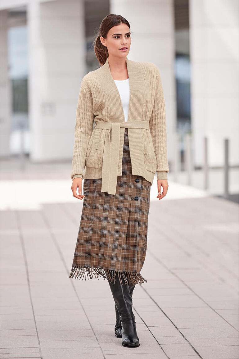 Frau in beigem Cardigan und Karo-Pencilskirt in moderner Umgebung