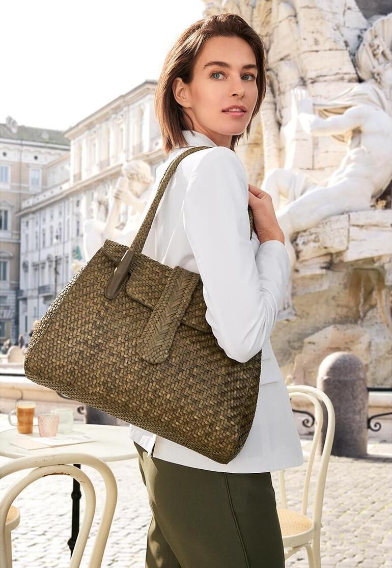 Khaki Frau trägt Allan K Flechtleder-Tote Bag in Olivgrün vor historischer Kulisse