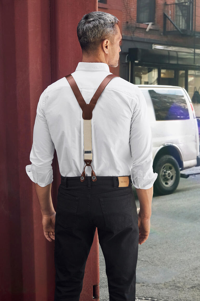 Mann mit Lederhosenträgern und weißem Hemd von hinten in der Stadt.