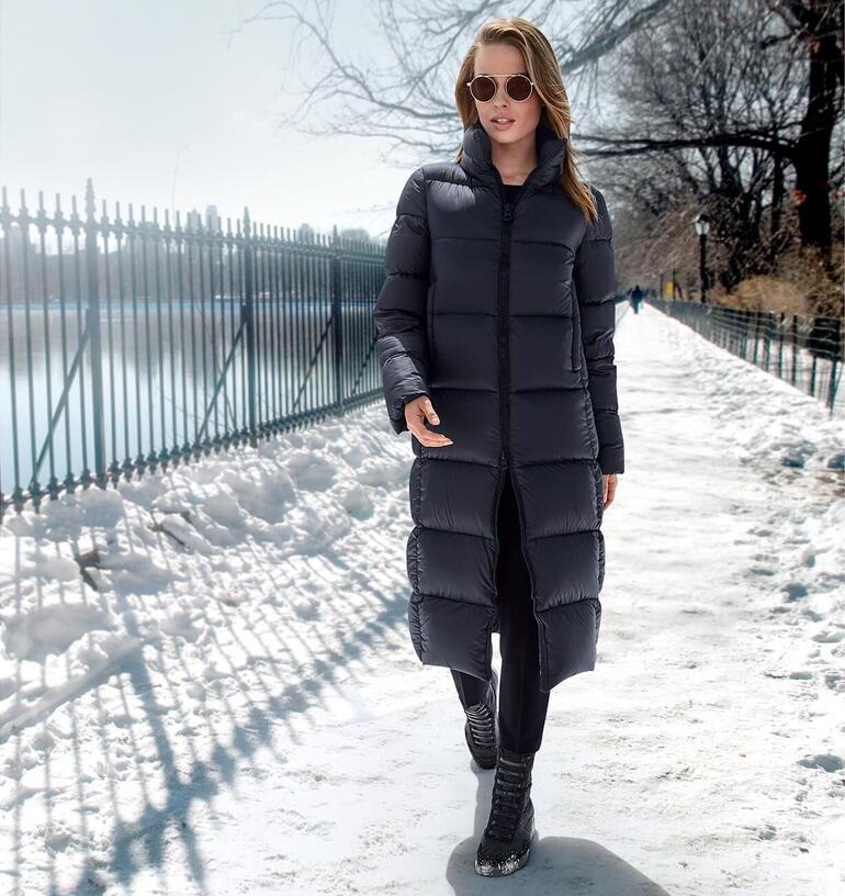 Schneiders Puffa Coat in Schwarz, getragen auf einem verschneiten Weg, mit Sonnenbrille.