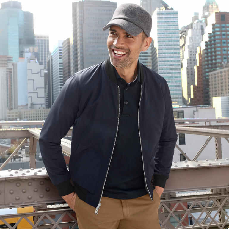 Mann mit Roeckl Walk-Kappe vor einer Stadtlandschaft