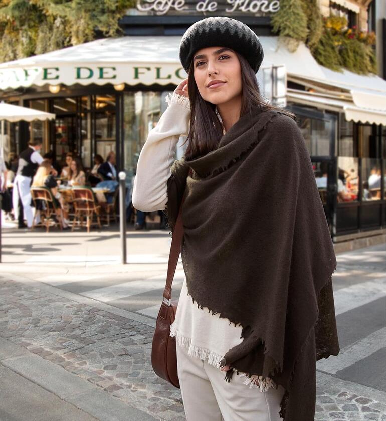 Nahaufnahme einer Frau mit braunem Fransen-Pullover und Hut.