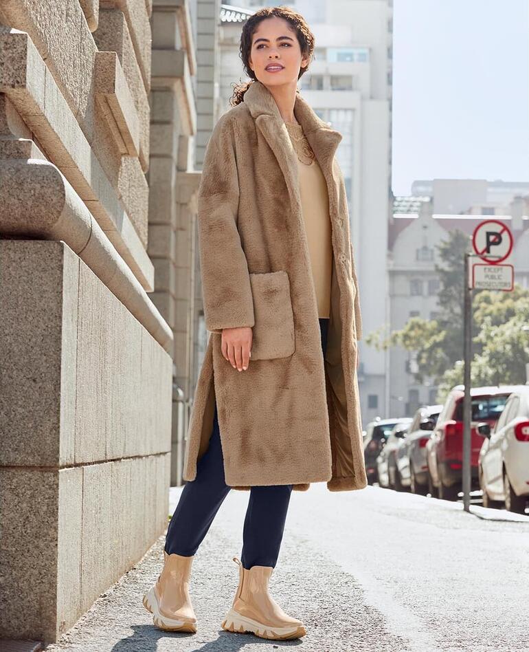 Frau in einer beigen Jacke und Chelsea-Sneakerboots auf der Straße
