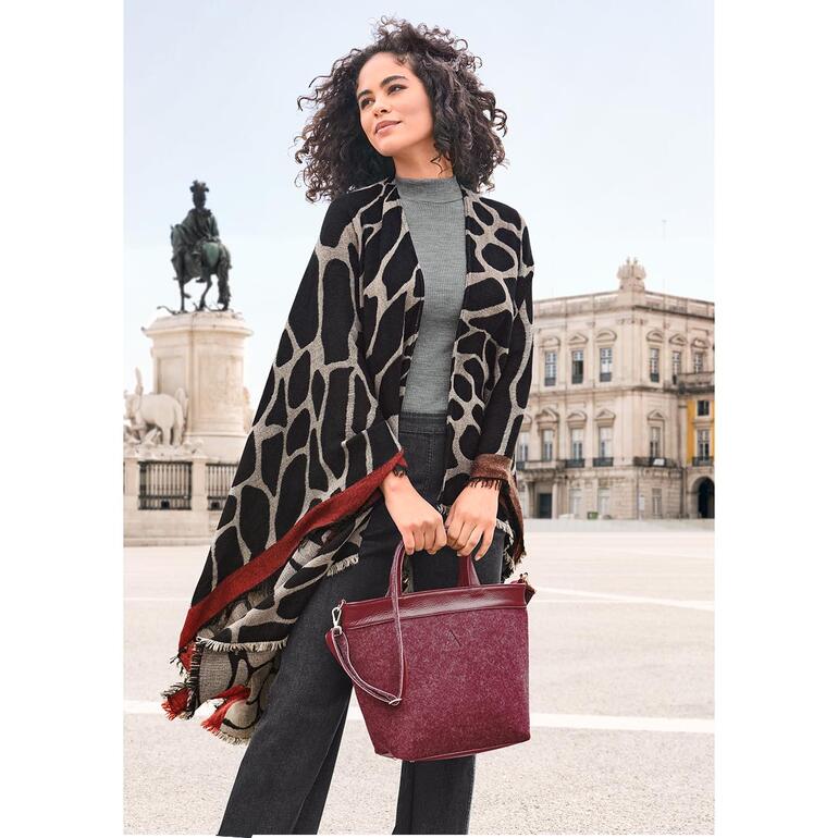 Ancini Wende-Poncho in verschiedenen Mustern, getragen von einer Frau in der Stadt.