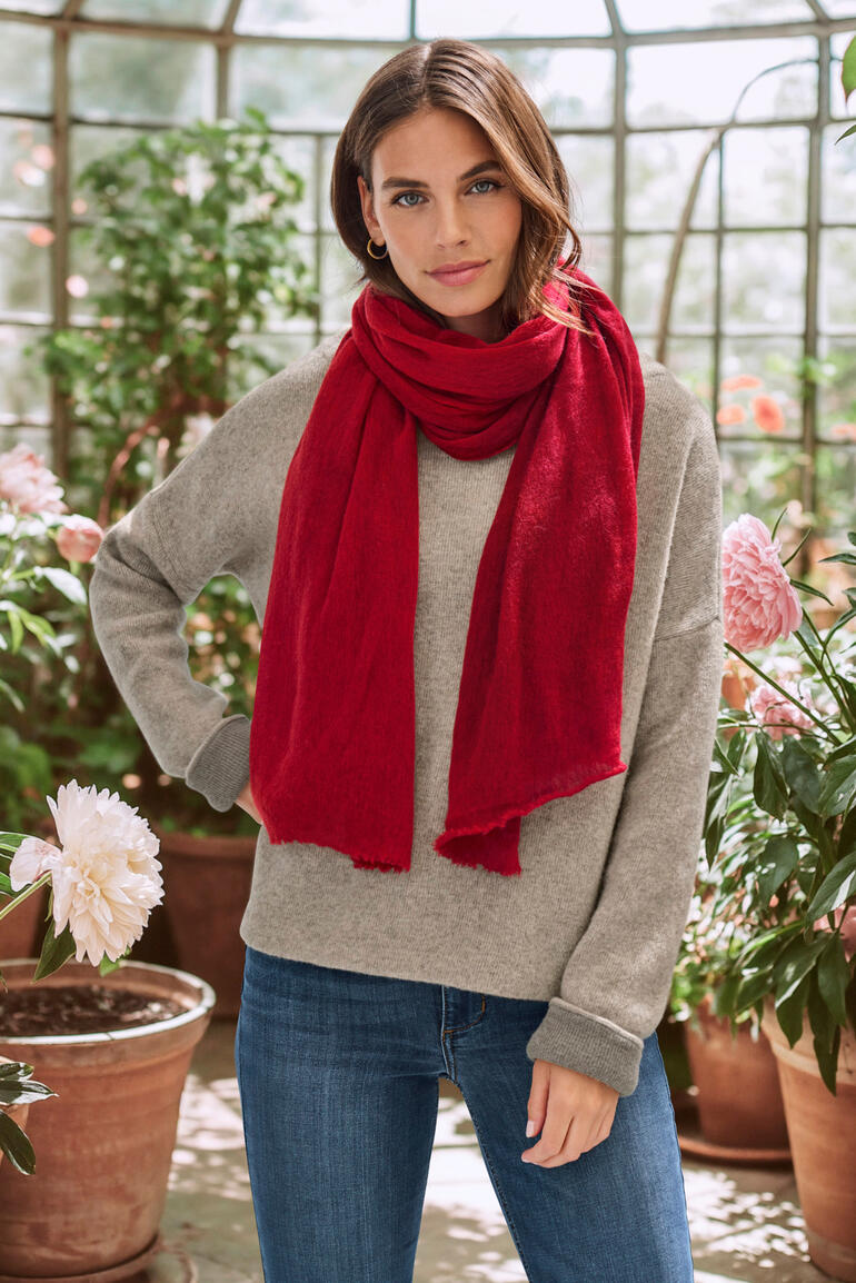 Frau trägt einen roten Cashmere-Schal in einem Garten.