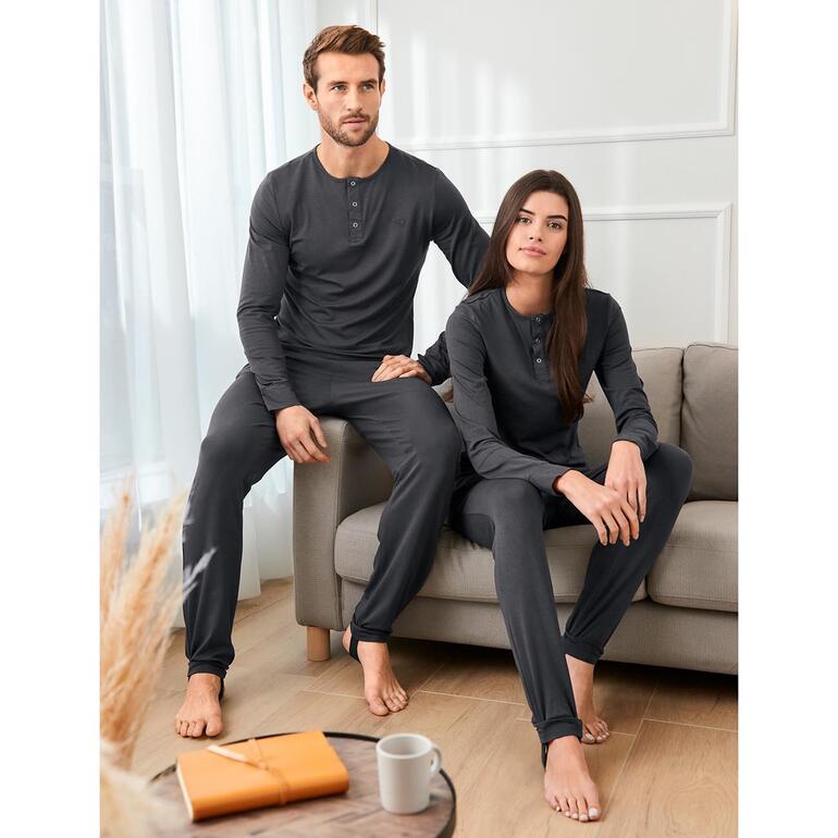 Paar in grauen Anti-Insekten-Pyjamas auf einem Sofa.