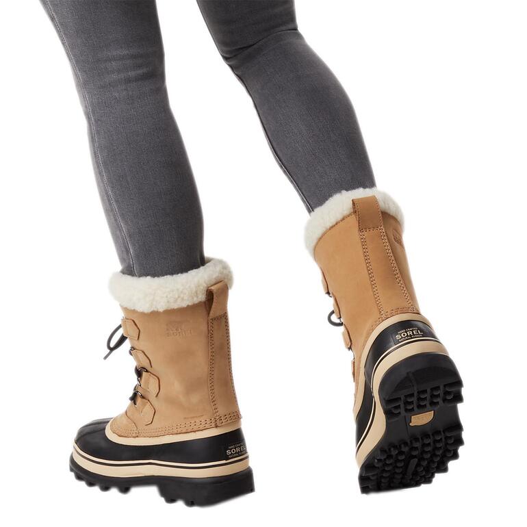 Frau trägt Sorel Winterboots 'Caribou' in Camel mit schwarzem Unterteil.