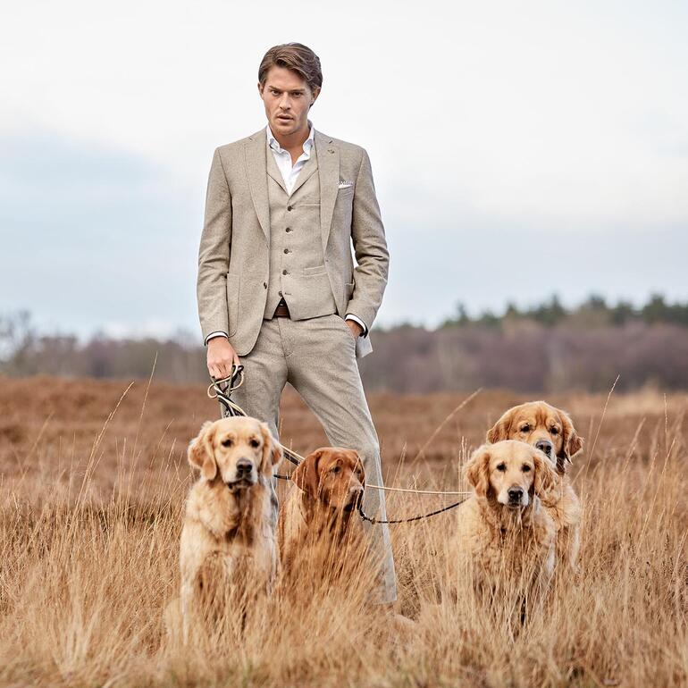 Mann im Soft-Donegal-Sakko mit drei Hunden im Freien.