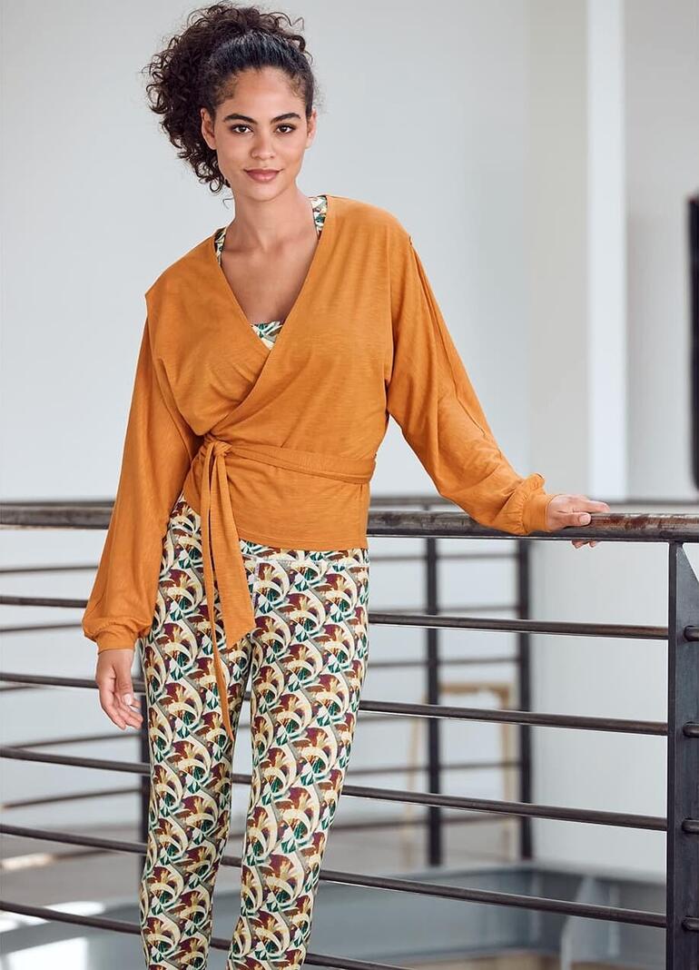 Frau in Mandala-Outfit mit Wickeljacke und Leggings, lächelt.
