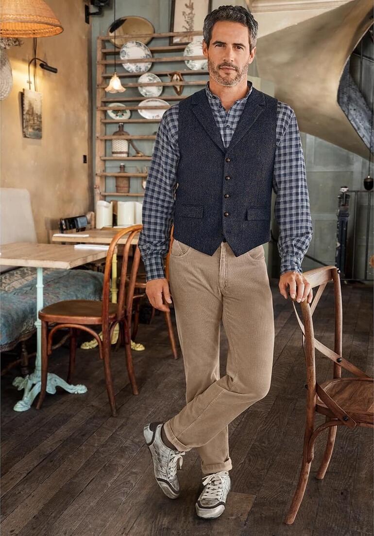 Five-Pocket-Edelcordhose Mann trägt eine dunkelgraue Tweed-Weste mit Karomuster