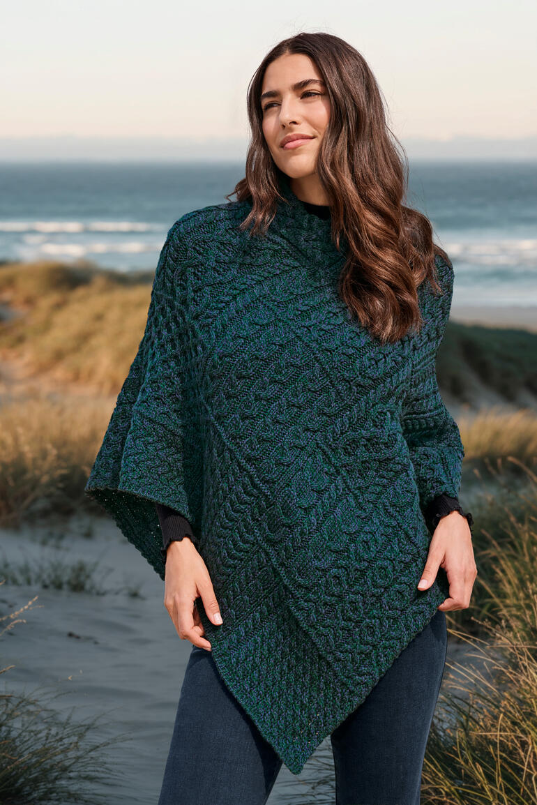 Atlantikblau Frau im Aran-Poncho posiert am Strand.