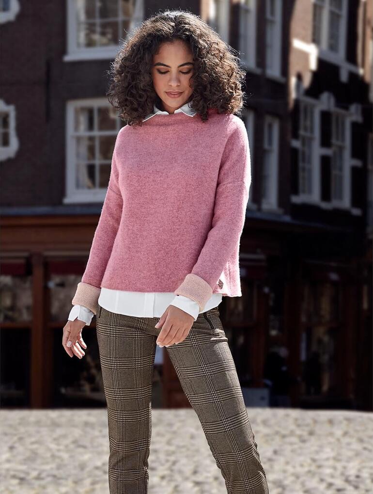 Frau mit rosa Walkpullover auf Pflasterstraße