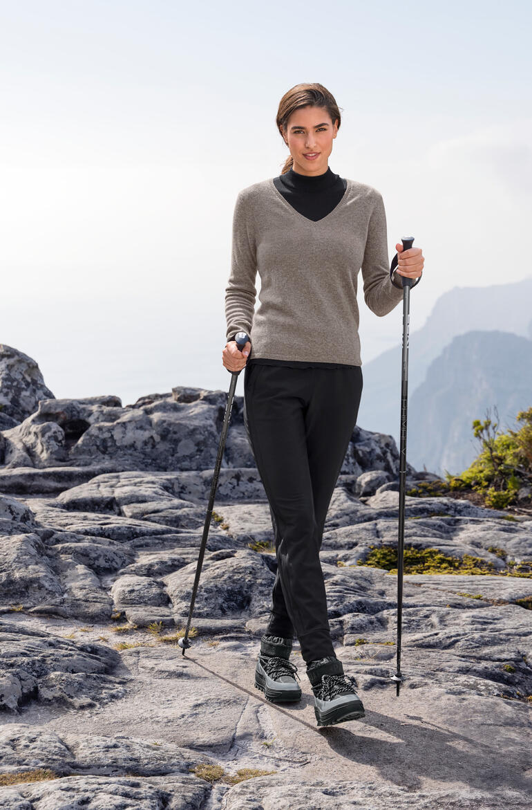 Frau in Taupe-Kaschmirpullover beim Wandern in den Bergen.