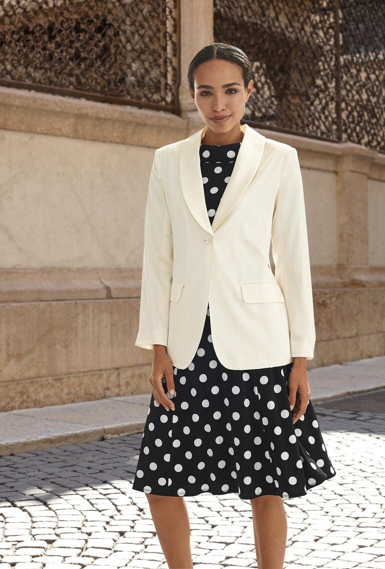 Weißer Seidenblazer über einem gepunkteten Kleid, eleganter Look.