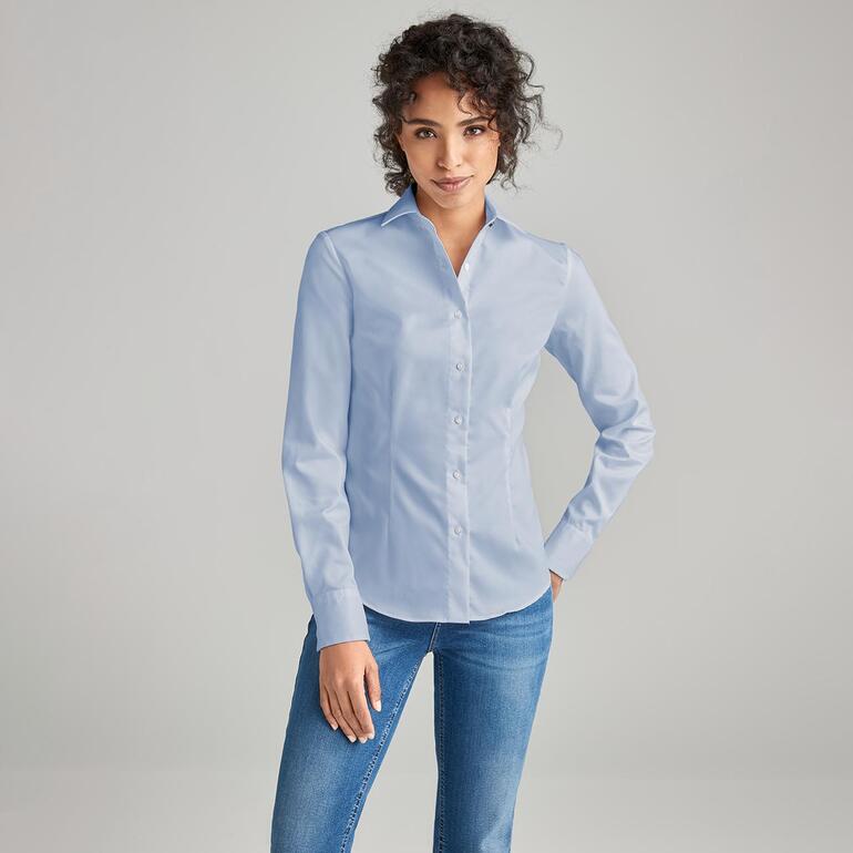 Frau trägt eine hellblaue QuickClean-Bluse, lächelt freundlich.