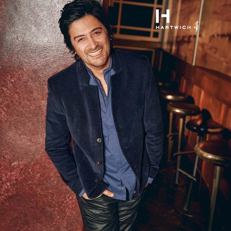 Mann lächelt in dunkelblauem Karo-Samt-Sakko