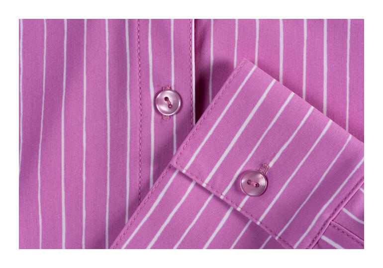 Detailaufnahme einer pink gestreiften Bluse mit Knöpfen.