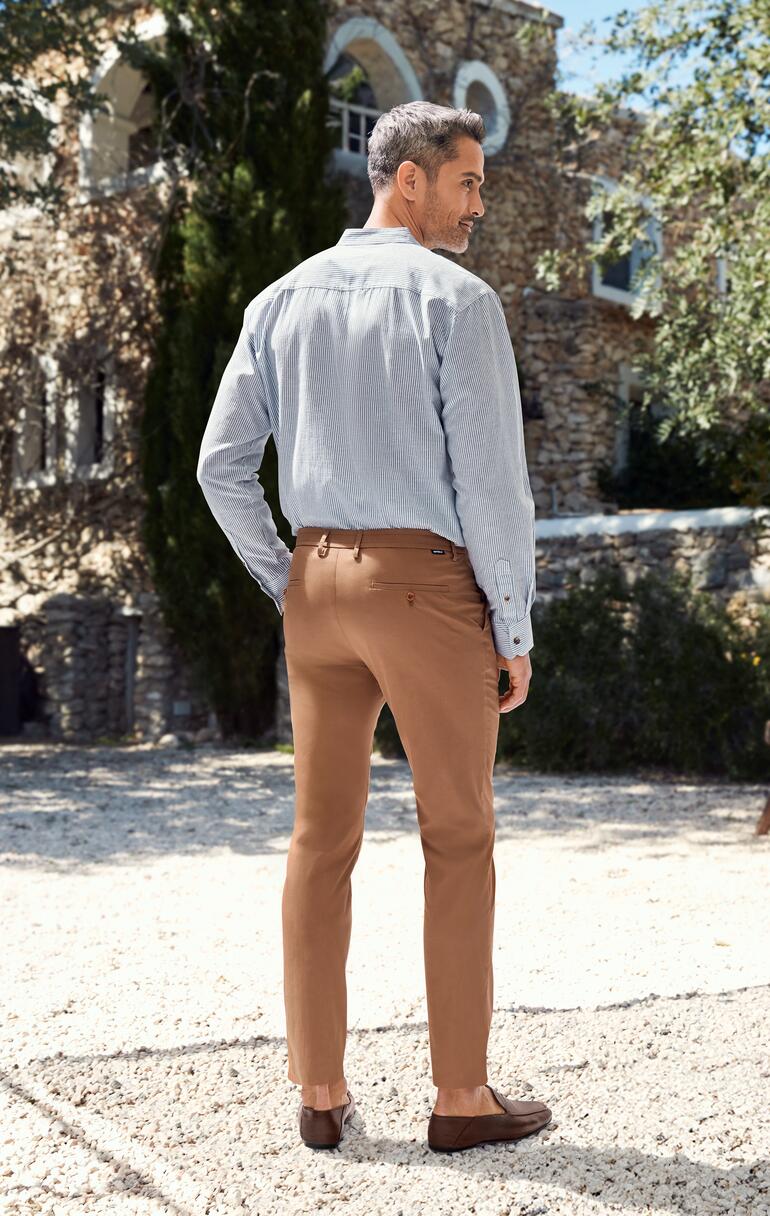 Mann in braunen Chinos von hinten, im Freien.