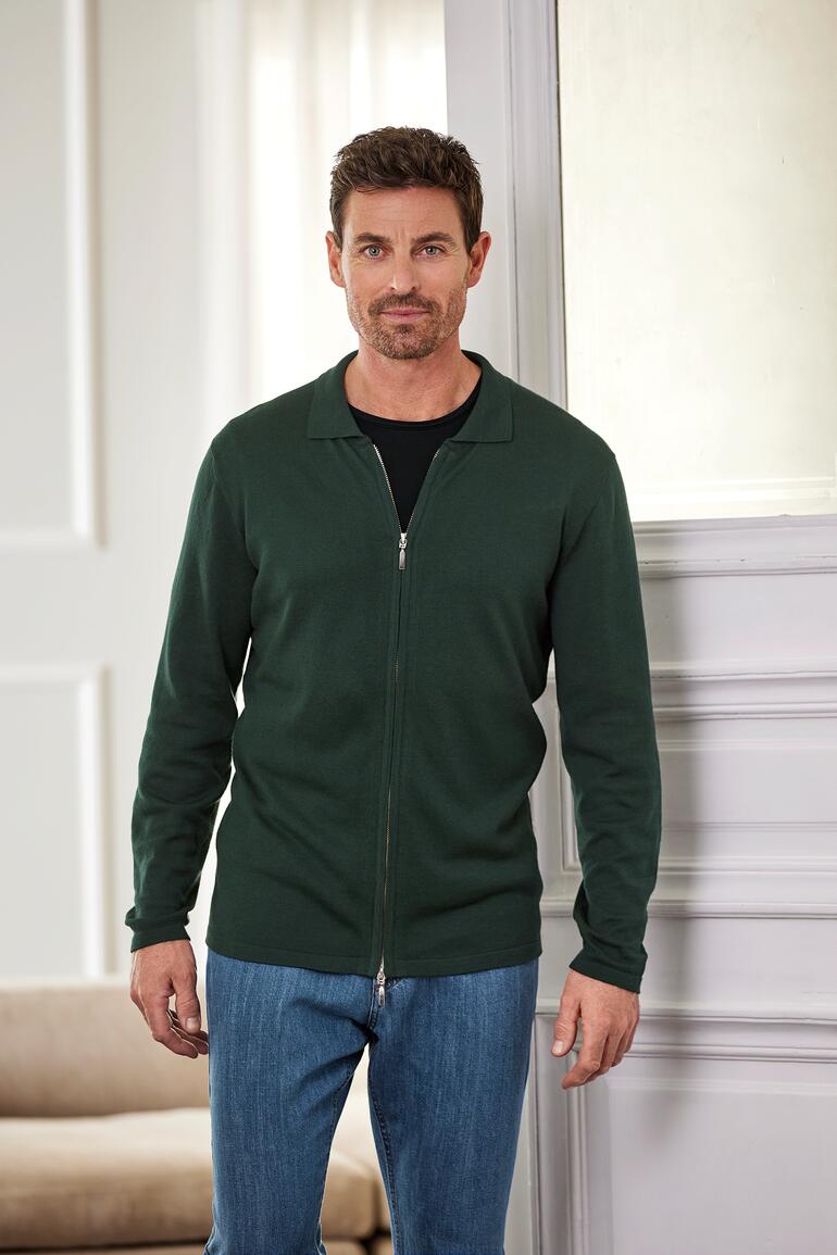 Mann in grüner Jacke und schwarzem T-Shirt mit einem Lächeln.