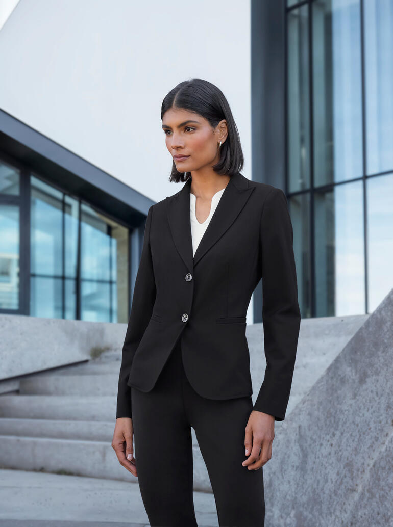 Schwarz Frau in eleganter Blazer-Kombination vor modernen Gebäuden