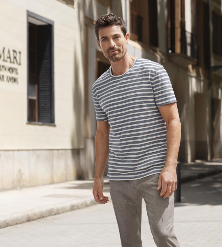 Junghans 1954 Jacquard-Streifen-T-Shirt Mann trägt gestreiftes T-Shirt und steht auf einer Stadtstraße