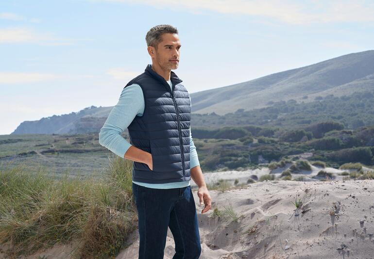 Mann trägt navy Ultraleicht-Daunenweste am Strand