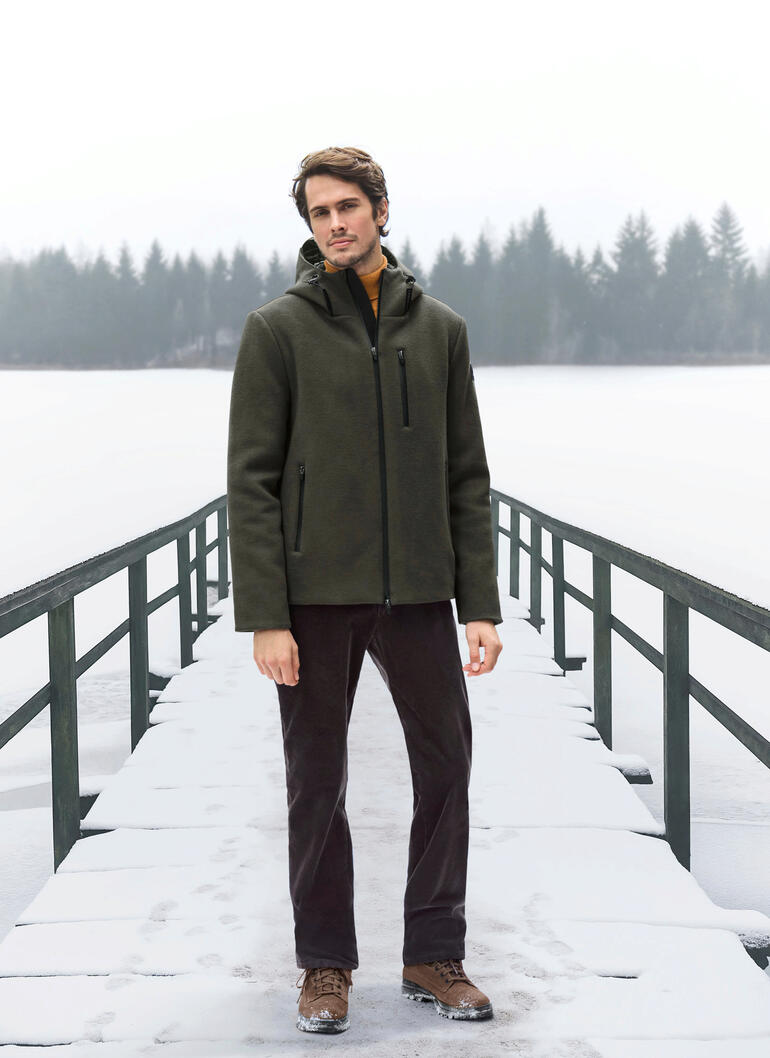Woll-Fleecejacke Mann in olivfarbener Woll-Fleecejacke steht auf einem schneebedeckten Steg.