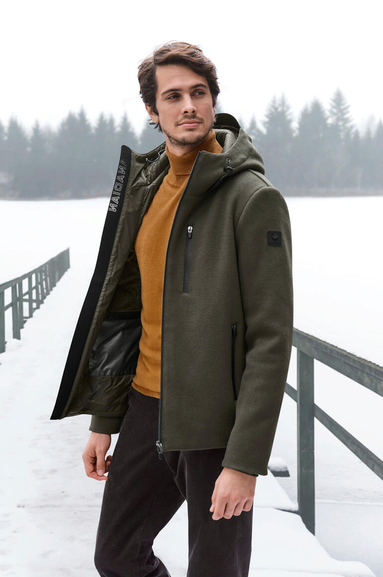 Mann in grüner Woll-Fleecejacke mit orangem Pullover am gefrorenen See.