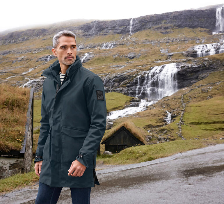 Mann in 3-in-1-Allwetter-Parka in einer Berglandschaft.