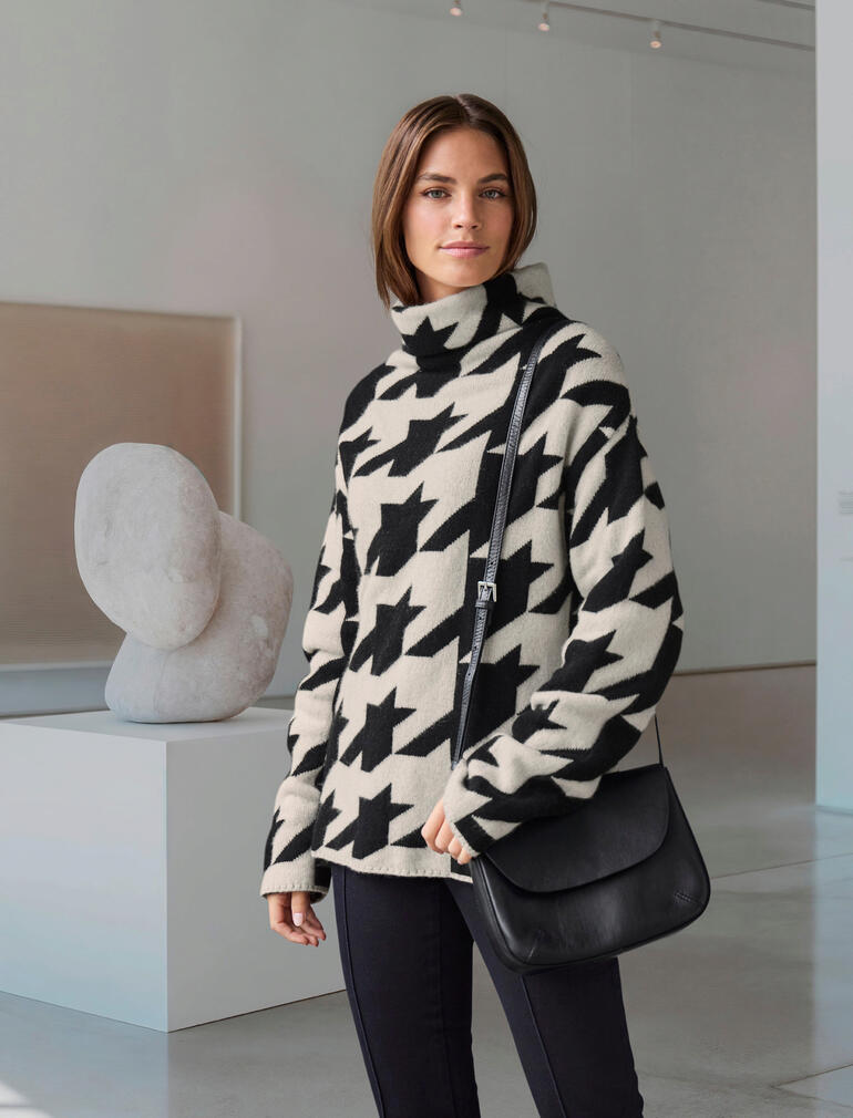 Junghans 1954 Hahnentritt-Kaschmir-Pulli Frau in einem schwarz-weißen Hahnentritt-Kaschmir-Pulli