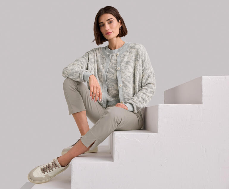 Pulli und Cardigan Frau sitzt auf einer Treppe, trägt ein graues 3D-Jacquard-Twinset.