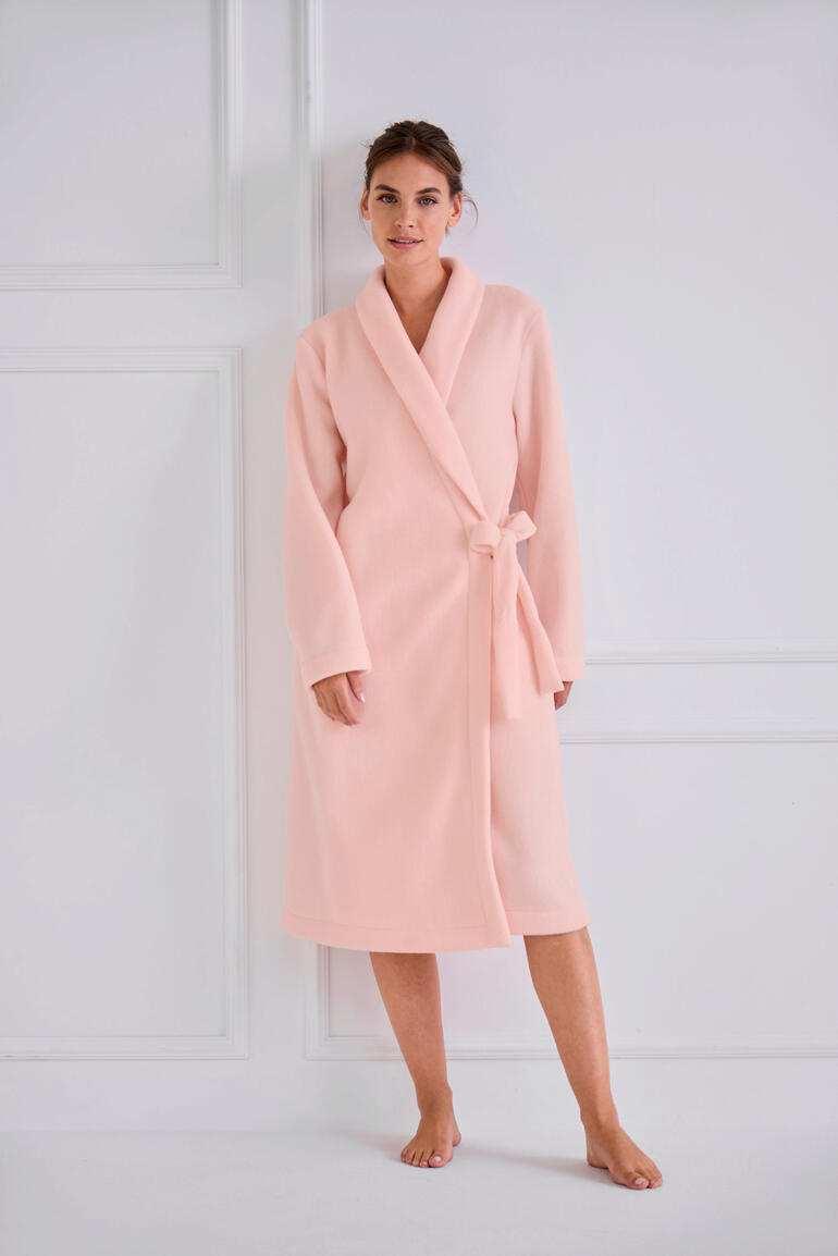 Frau in einem rosa Fleece-Morgenmantel, steht in voller Länge.
